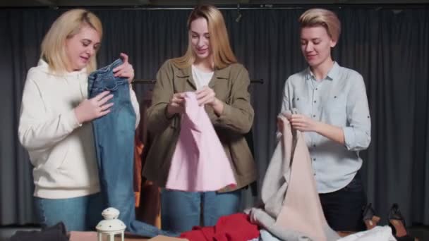 Jeunes femmes Travailleurs d'occasion trier les vêtements sur la table — Video