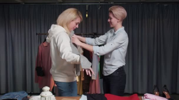 Vrouw probeert op een grijze trui in tweedehands kleding winkel — Stockvideo
