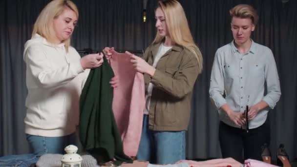 Νεαρές γυναίκες Εργάτες μεταχειρισμένων καταστημάτων ταξινομήσετε τα ρούχα στο τραπέζι — Αρχείο Βίντεο