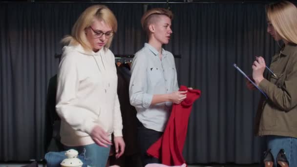 Jonge vrouwen Tweedehands winkelpersoneel sorteren kleding op tafel — Stockvideo