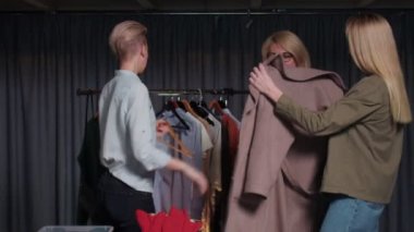 Genç bir kadın ikinci el giysi dükkanında pembe bir ceket deniyor.