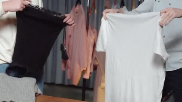 Primer plano de las mujeres Trabajadoras de segunda mano clasifican la ropa en la mesa — Vídeo de stock