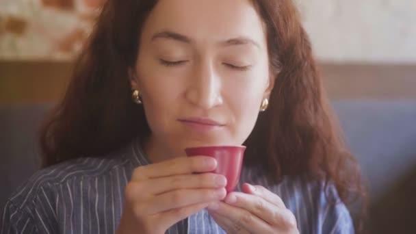 Красивая кудрявая девушка пробует чай и наслаждается вкусом — стоковое видео