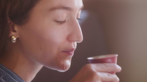 Una hermosa chica de pelo rizado prueba el té y disfruta del sabor — Vídeos de Stock