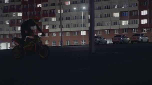 Fiatal őrült nő fekete sisakban trükköket csinál a motoron éjszaka — Stock videók