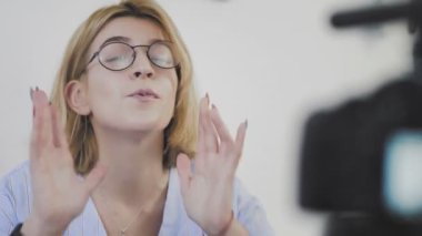 Kamerayı açıp gülümseyen ve kameraya konuşan genç bir kadının yakın çekimi. İzleyicilerinize selamlar.