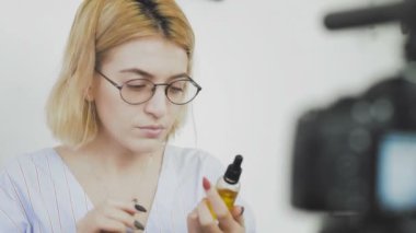 Gözlüklü, gülümseyen ve kameraya yeni bir alışveriş hakkında konuşan genç bir kadının yakın çekimi. Kişisel bakım için kozmetik incelemesi