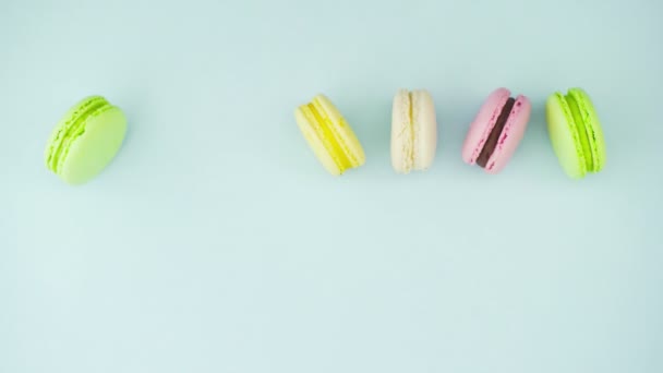 Vista superior de biscoitos Macarons franceses multicoloridos e uma xícara de café em um fundo azul pastel — Vídeo de Stock