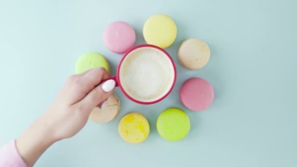 Vue de dessus des biscuits Macarons français multicolores et une tasse de café sur un fond bleu pastel — Video