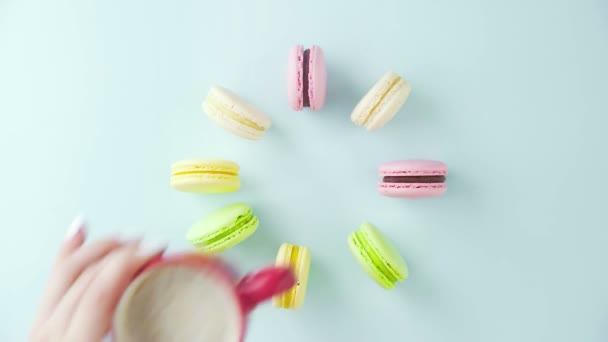 Κάτοψη των πολύχρωμων γαλλικών μπισκότων Macarons και ένα φλιτζάνι καφέ σε παστέλ μπλε φόντο — Αρχείο Βίντεο