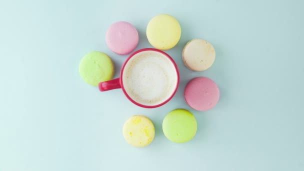 Κάτοψη των πολύχρωμων γαλλικών μπισκότων Macarons και ένα φλιτζάνι καφέ σε παστέλ μπλε φόντο — Αρχείο Βίντεο