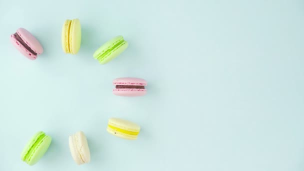 Vista superior de galletas de macarrones franceses multicolores y una taza de café sobre un fondo azul pastel — Vídeo de stock