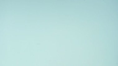 Çok renkli kurabiyelerin üst görüntüsü pastel mavi arka planda Fransız makarnaları. Bir kadının eli kurabiyeyi ortaya taşır..