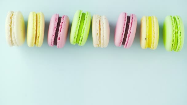 Draufsicht auf bunte französische Macarons-Kekse auf pastellblauem Hintergrund — Stockvideo