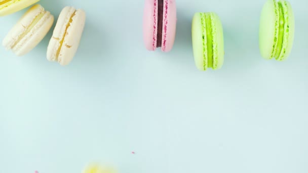 Bovenaanzicht van veelkleurige Franse Macarons koekjes op een pastelblauwe achtergrond — Stockvideo