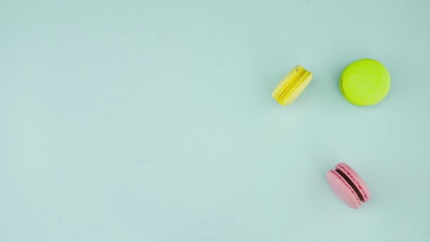 Vista superior de galletas de macarrones franceses multicolores y una taza de café sobre un fondo azul pastel — Vídeos de Stock