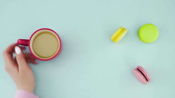 Bovenaanzicht van veelkleurige Franse Macarons koekjes en een kop koffie op een pastelblauwe achtergrond — Stockvideo