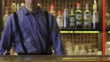 Barmen bir bardak getirdi, alkollü bir kokteyl, ve tezgahın üzerine koydu. Yakın plan.