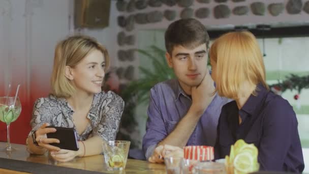 Een jongen en twee meisjes in een bar communiceren, glimlachen. — Stockvideo