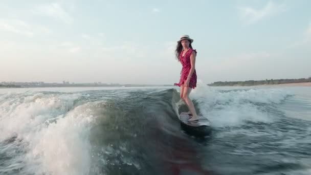 Surfařka v červených šatech a klobouku skočí na wakeboard. Zkušený wakeboarder rozstřikuje do kamery kapky vody. — Stock video