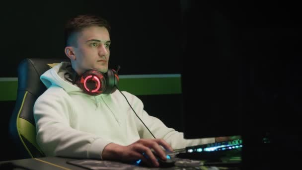 一个年轻的游戏玩家用耳机在电脑上玩 — 图库视频影像