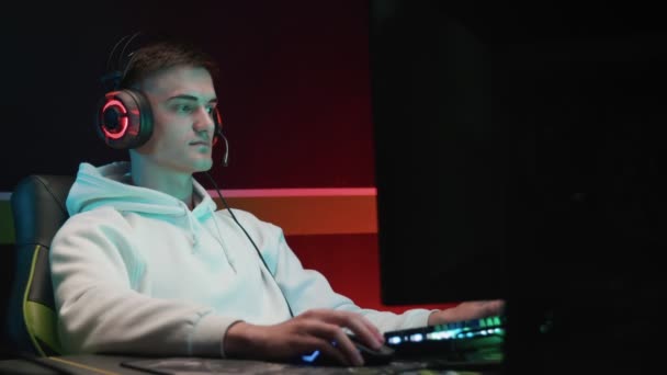 Молодий геймер грає на комп'ютері з навушниками — стокове відео