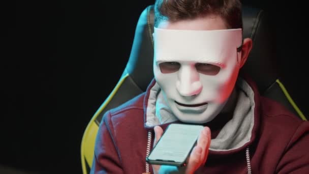 Ein Mann mit Maske sitzt da und liest einen Text von einem Telefon in Großaufnahme — Stockvideo