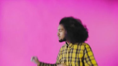 Pembe arka planda Afrikalı saç stili olan genç bir adam dans ediyor. Renkli bir arkaplanda dans etmek.