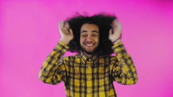 Mladý muž s africkým účesem na růžovém pozadí je šťastný. Emoce na barevném pozadí. — Stock video