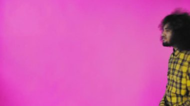 Pembe arka planda Afrikalı saç stili olan genç bir adam telefonunu çıkardı, mesaja baktı ve cebine geri koydu. Renkli bir arkaplanda duygular