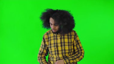 Yeşil arka planda Afrikalı saç stili olan genç bir adam telefonunu çıkarır, mesaja bakar ve cebine geri koyar. Renkli bir arkaplanda duygular