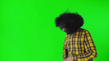 Yeşil arka planda Afrikalı saç stili olan genç bir adam telefonunu çıkarır, mesaja bakar ve cebine geri koyar. Renkli bir arkaplanda duygular