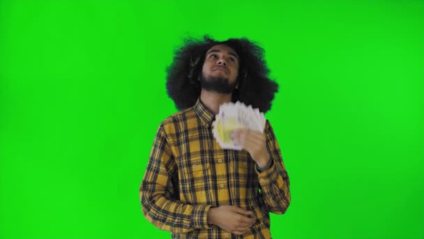 緑の背景に孤立して立って、カメラを見て、彼の手に紙幣のファンを保持し、幸せなアフリカ系アメリカ人の男 — ストック動画