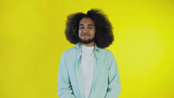 Портрет молодого афроамериканца, счастливого парня, стоящего на желтом фоне и улыбающегося в камеру. — стоковое видео