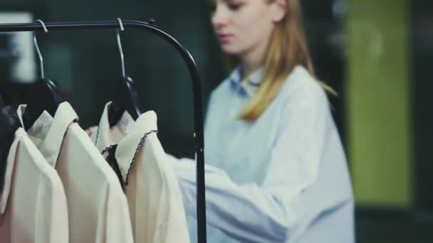 En söt tjej väljer kläder i en butik. Shopping — Stockvideo
