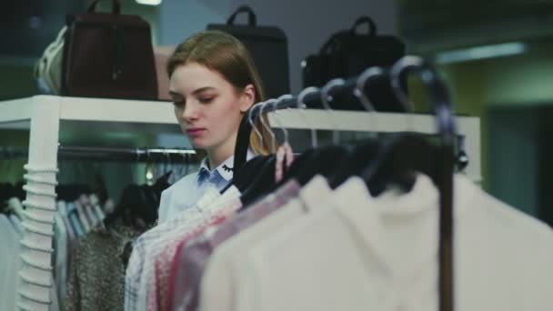 Une jolie fille choisit des vêtements dans un magasin. Shopping — Video