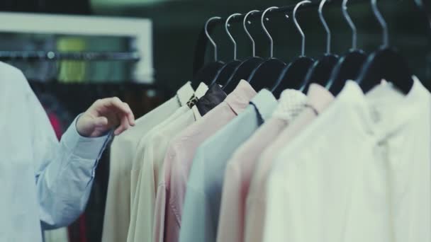 Uma menina bonito escolhe roupas em uma loja. Compras. Close-up — Vídeo de Stock