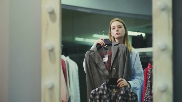 Une jolie fille essaie des vêtements dans la cabine d'essayage d'un magasin de vêtements. Shopping — Video