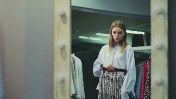 En söt flicka provar kläder i provrummet i en klädaffär. Shopping — Stockvideo