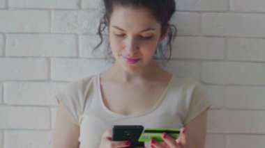 Genç bir kadın telefonuyla kanepede oturuyor ve alışveriş yapıyor.