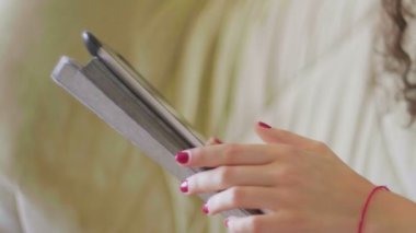 Kanepede oturup interneti karıştıran tabletli genç bir kadının yakın çekimi..