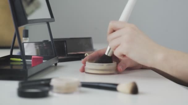 Salón de belleza en casa. Un primer plano de una mano femenina irreconocible aplicando polvo a un cepillo, maquillándose todos los días en casa — Vídeos de Stock