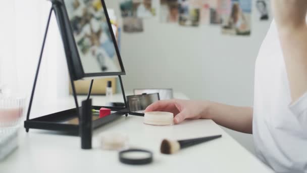Skönhetssalong. En närbild av en oigenkännlig kvinnlig hand som applicerar puder på en borste, gör vardaglig makeup hemma — Stockvideo