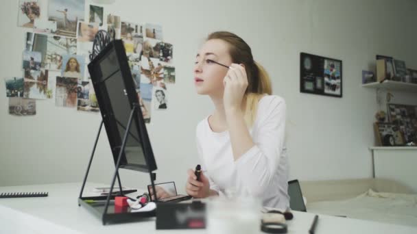 Make-up im Gesicht. Eine junge Frau bemalt ihre langen Wimpern mit schwarzer Mascara. — Stockvideo