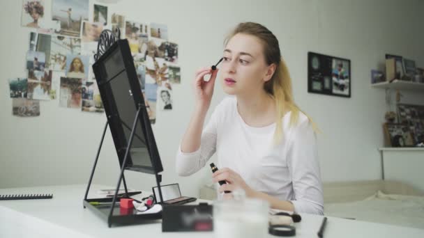 Smink i ansiktet. En ung kvinna målar sina långa ögonfransar med svart mascara. — Stockvideo