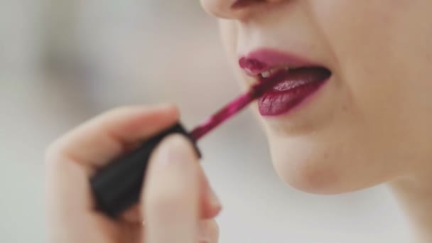 La fille peint ses lèvres avec du rouge à lèvres. Gros plan du visage. Macro photographie d'une femme portant du rouge à lèvres. La macro du visage. La fille se regarde dans un petit miroir — Video