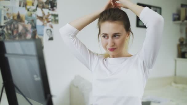 Krásná mladá žena dělá culík na hlavě před zrcadlem — Stock video