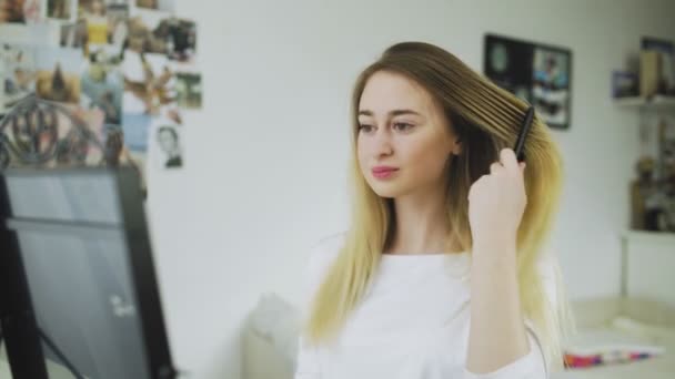 Bella giovane donna pettina i capelli davanti allo specchio — Video Stock