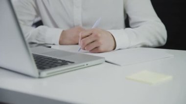 Tanınmayan bir adam kağıda not alır. Uzaktan kumanda. Serbest çalışıyorum. Video hareket halinde. Yakın plan.