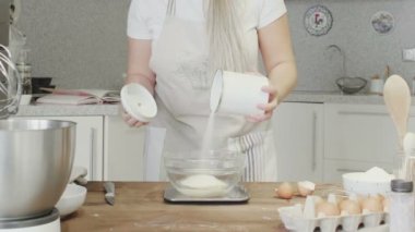 Mutfakta bir kız cam bir kaseye un döküyor.